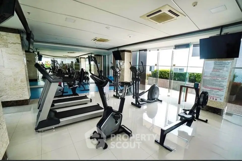 Spacious modern gym with state-of-the-art equipment and large windows offering a scenic view.