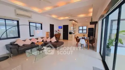 Spacious modern living room with open kitchen and dining area, featuring elegant decor and ample natural light.