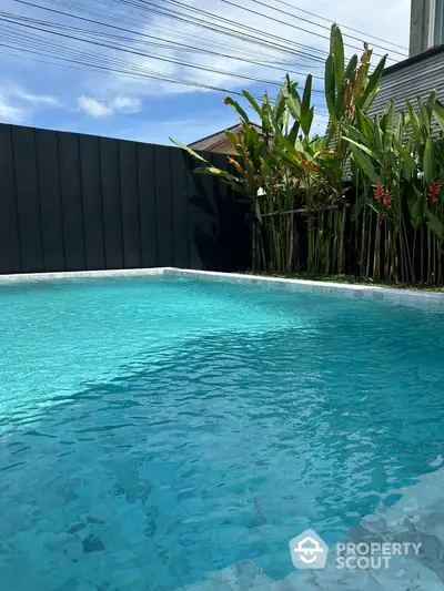 Luxurious private pool with lush greenery and modern fencing