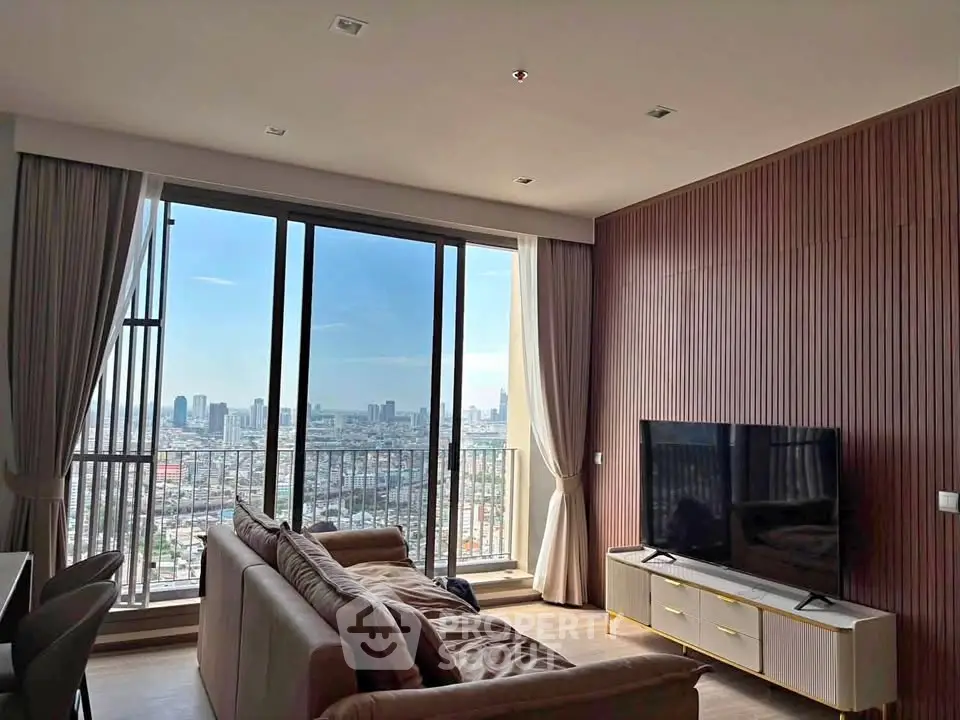 Modern living room with large windows offering stunning city views, featuring cozy seating and sleek entertainment setup.