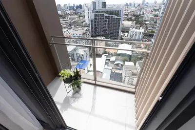 Stunning city view from a modern high-rise balcony with sleek railing and potted plants.