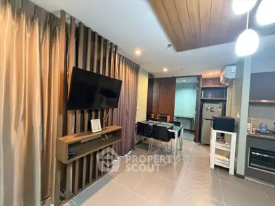 Modern living room with open kitchen, stylish decor, and wall-mounted TV in a cozy apartment.