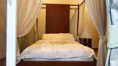 Cozy bedroom with elegant canopy bed and soft lighting, perfect for relaxation.