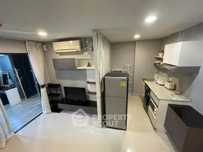 Modern open-layout living room and kitchen with sleek appliances and stylish decor.