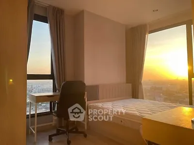 Sunlit bedroom with city view, featuring a desk and bed, perfect for serene living.