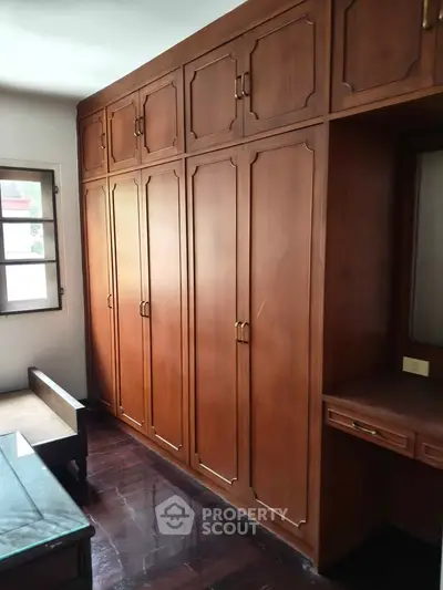 Spacious bedroom with elegant wooden built-in wardrobes and natural light.