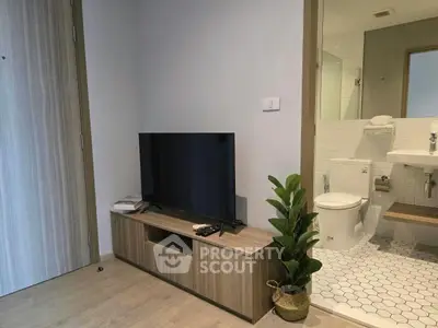 Modern living room with TV, wooden cabinet, and view into stylish bathroom.