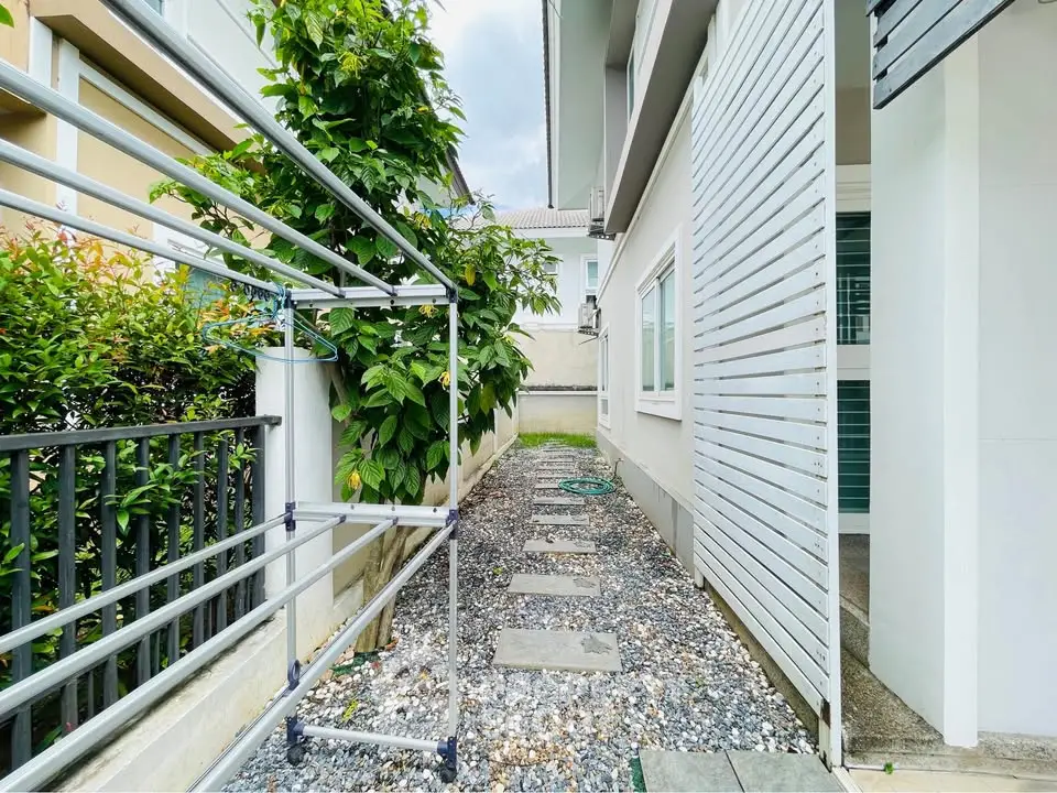 Charming side yard with pebble pathway and lush greenery, perfect for outdoor relaxation and gardening.