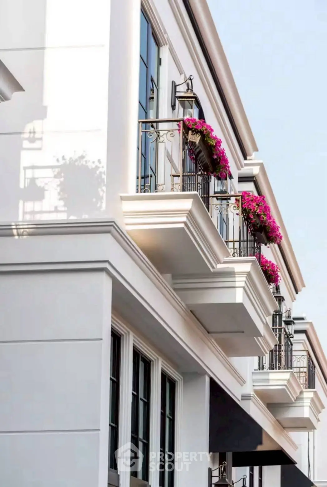 Elegant building facade with charming balconies and vibrant flower arrangements.