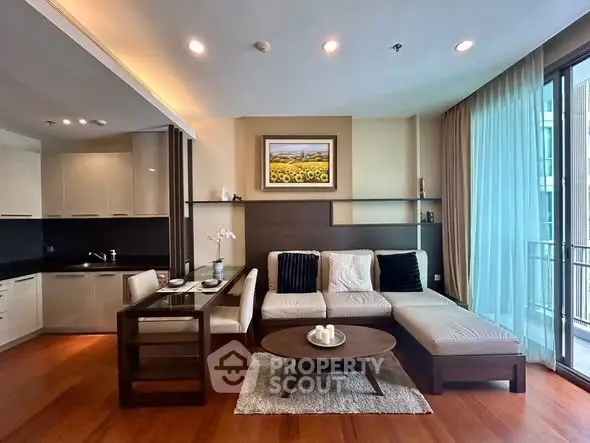 Modern living room with open kitchen and balcony view, featuring elegant decor and cozy seating.