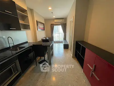 Modern kitchen with sleek black cabinets and open layout, featuring a cozy dining area and natural light.