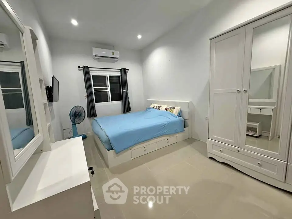 Spacious bedroom with modern furnishings and ample storage in a cozy real estate property.