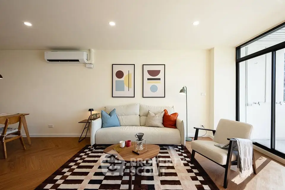 Modern living room with stylish decor, cozy seating, and natural light from large windows.