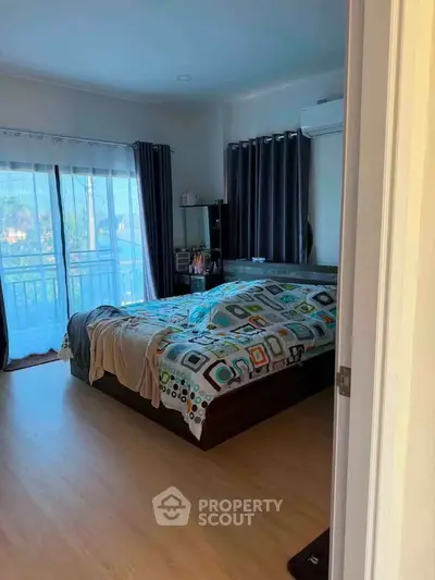 Cozy bedroom with large window and balcony access, featuring modern decor and ample natural light.
