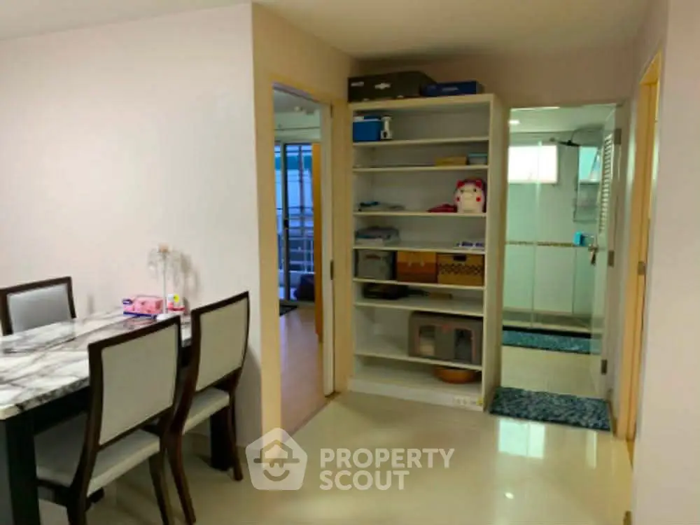 Spacious dining area with open shelving and adjacent bathroom in modern apartment.