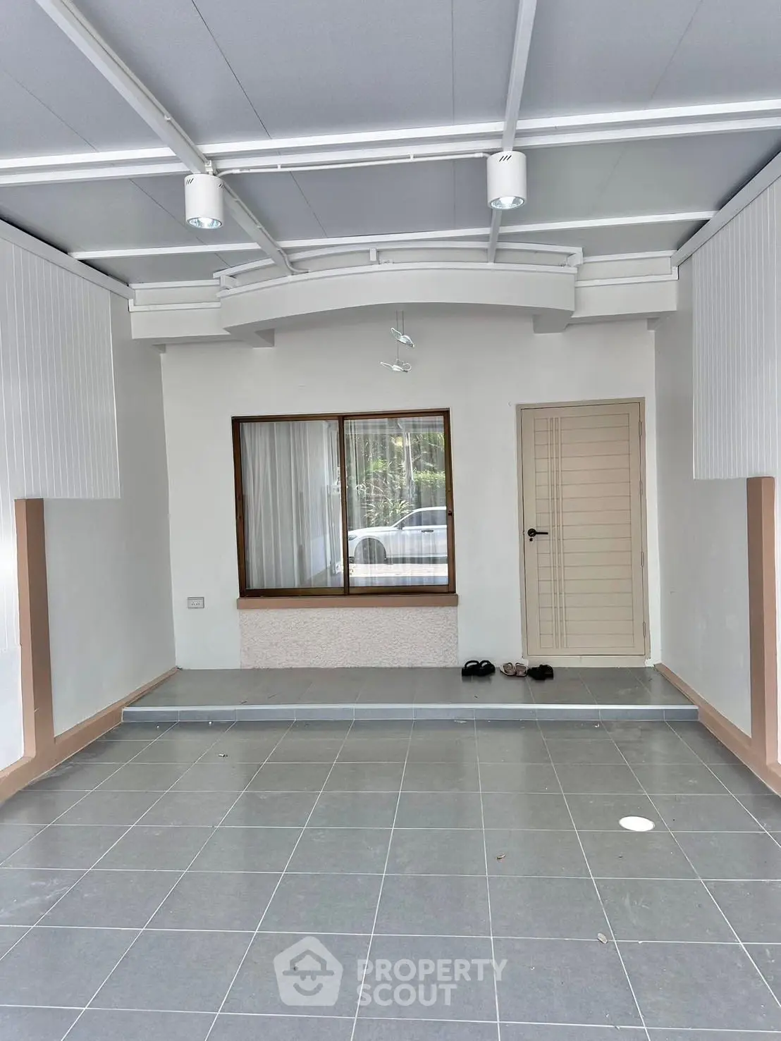 Spacious tiled entrance with modern lighting and large window, perfect for welcoming guests.
