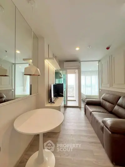 Modern living room with sleek design, featuring a leather sofa, wall-mounted TV, and large windows for natural light.