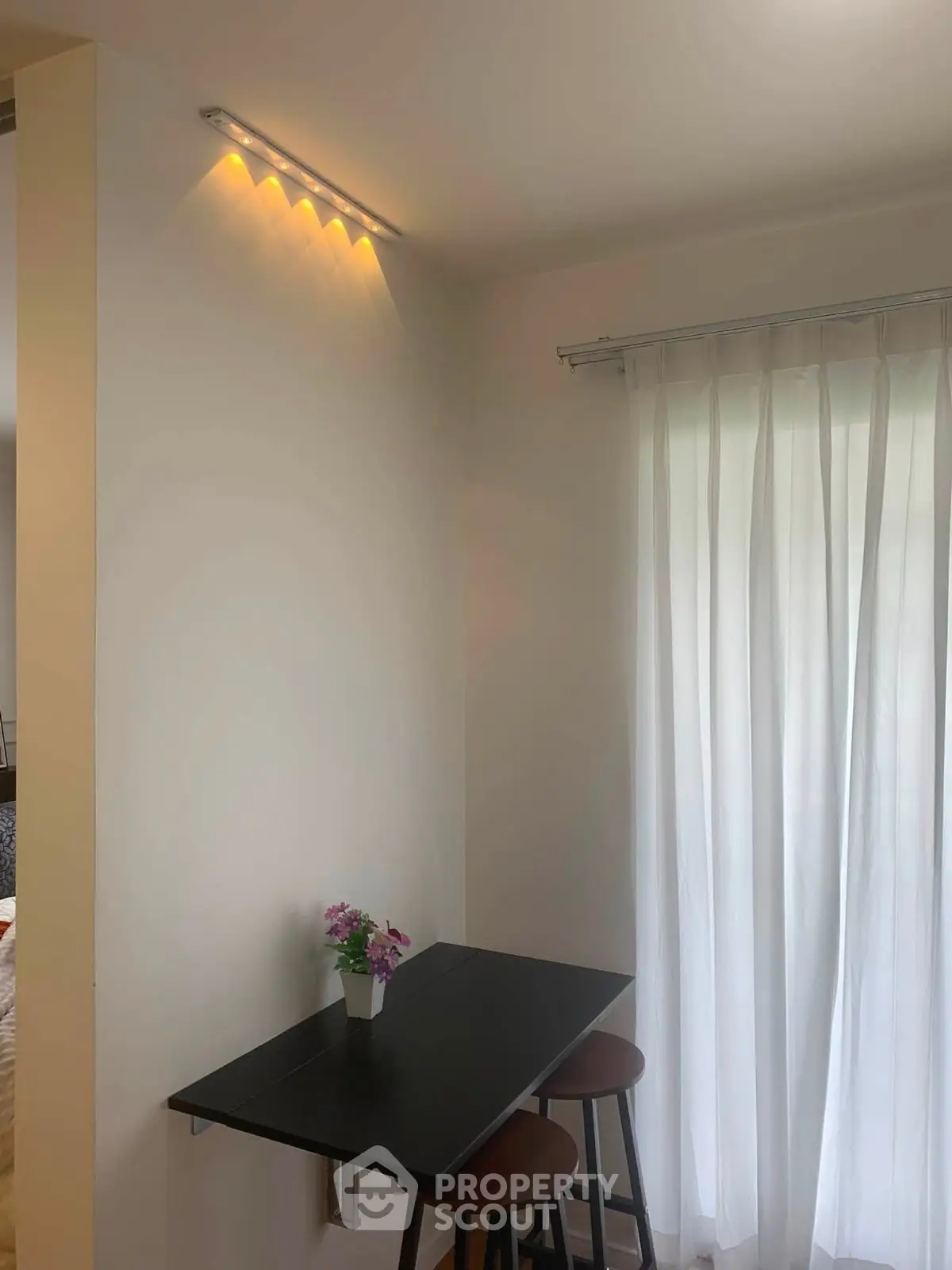 Cozy dining nook with modern lighting and natural light from sheer curtains.
