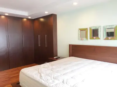 Spacious bedroom with elegant wooden wardrobe and cozy bed setup.