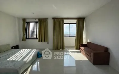 Spacious bedroom with large windows and natural light, featuring a cozy sofa and minimalist decor.