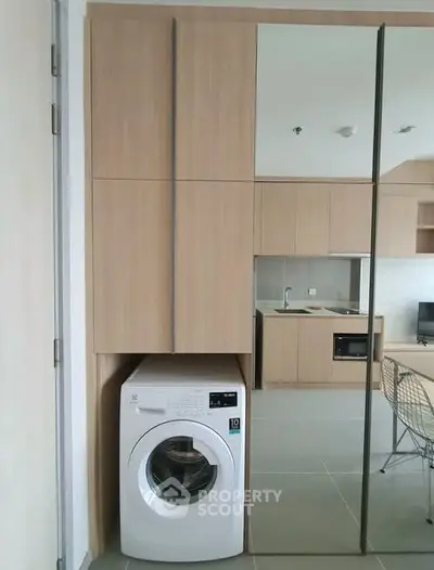 Modern apartment interior with built-in washing machine and sleek kitchen design.