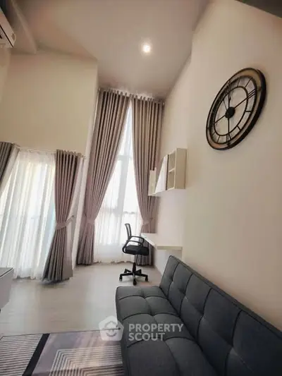 Modern living room with high ceilings, large windows, and stylish furniture