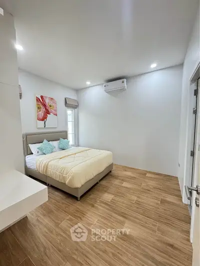 Modern bedroom with wooden flooring and stylish decor in a bright, airy space.