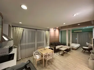 Modern open-plan living room with cozy seating and dining area, featuring elegant lighting and stylish decor.