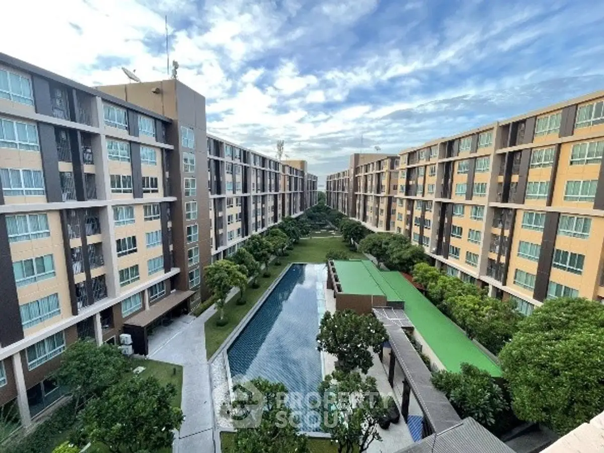 Stunning aerial view of modern apartment complex with central pool and lush greenery.