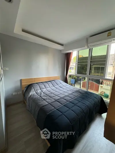 Cozy bedroom with large window and modern decor in a bright apartment.