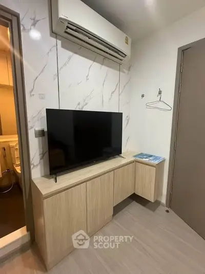 Modern living room with air conditioning and sleek TV setup in stylish apartment.