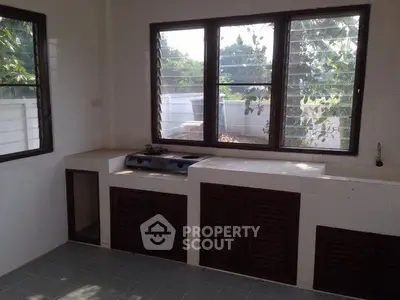 Spacious kitchen with large windows and ample natural light, featuring a built-in gas stove and storage cabinets.