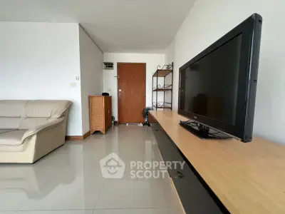 Spacious living room with modern TV setup and comfortable seating in a stylish apartment.