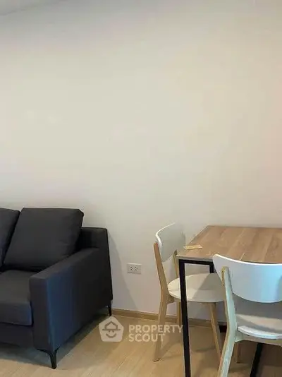 Cozy living room with modern sofa and dining table, perfect for small gatherings.