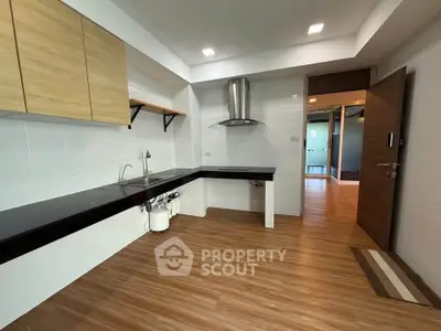 Modern kitchen with sleek black countertops and wooden cabinets in a spacious apartment.