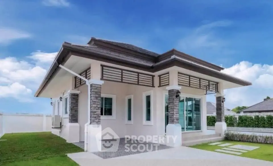 Charming single-story house with modern design and lush green lawn under a clear blue sky.