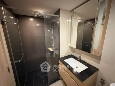 Modern bathroom with sleek glass shower and elegant vanity in contemporary apartment.