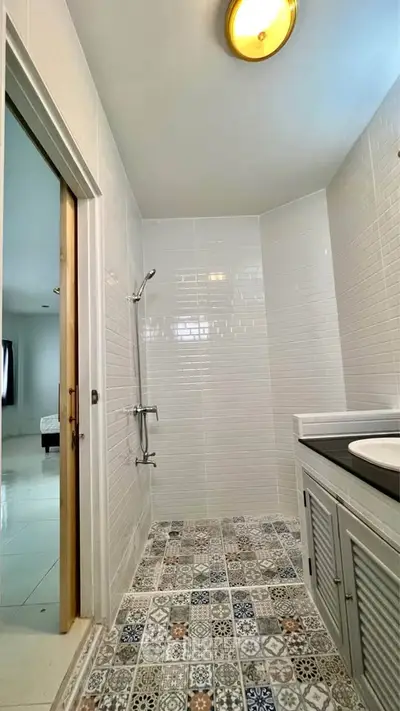 Modern bathroom with stylish tile flooring and sleek fixtures, adjacent to a bright bedroom.