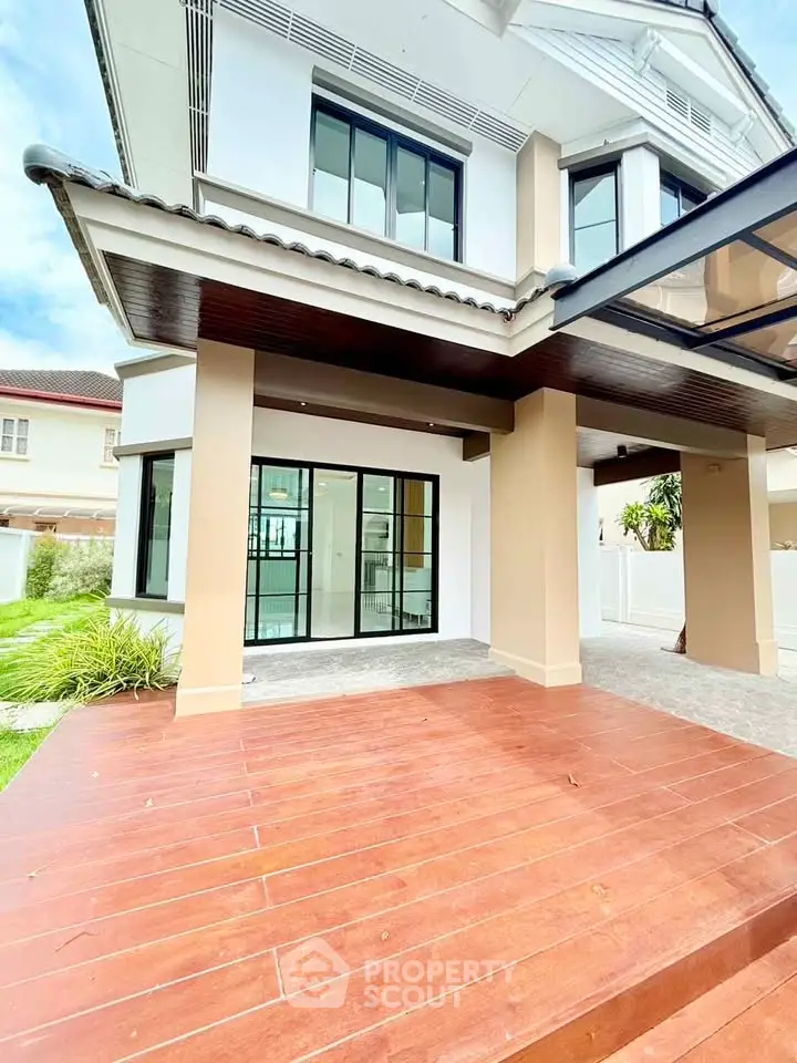 Stunning modern house exterior with spacious wooden deck and large glass doors, perfect for indoor-outdoor living.