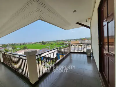 Spacious balcony with stunning panoramic view of lush green fields and cityscape, perfect for relaxation.
