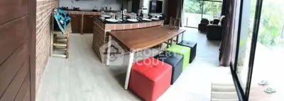 Spacious modern kitchen with open layout and vibrant seating, overlooking lush greenery.