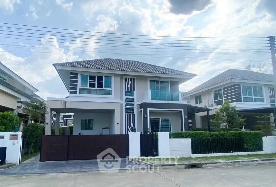 Modern two-story house with sleek design and spacious driveway in a suburban neighborhood.