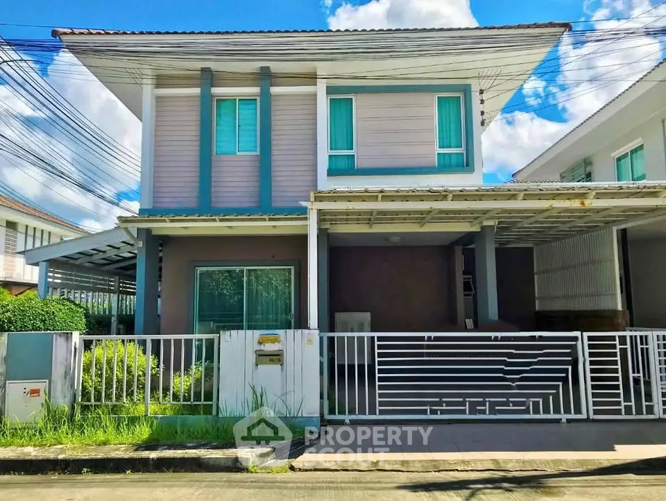 Modern two-story house with gated entrance and carport in a suburban neighborhood.
