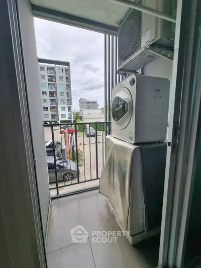 Compact balcony with washing machine and city view, perfect for urban living.