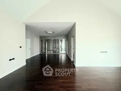 Spacious modern living room with dark wood flooring and ample natural light.