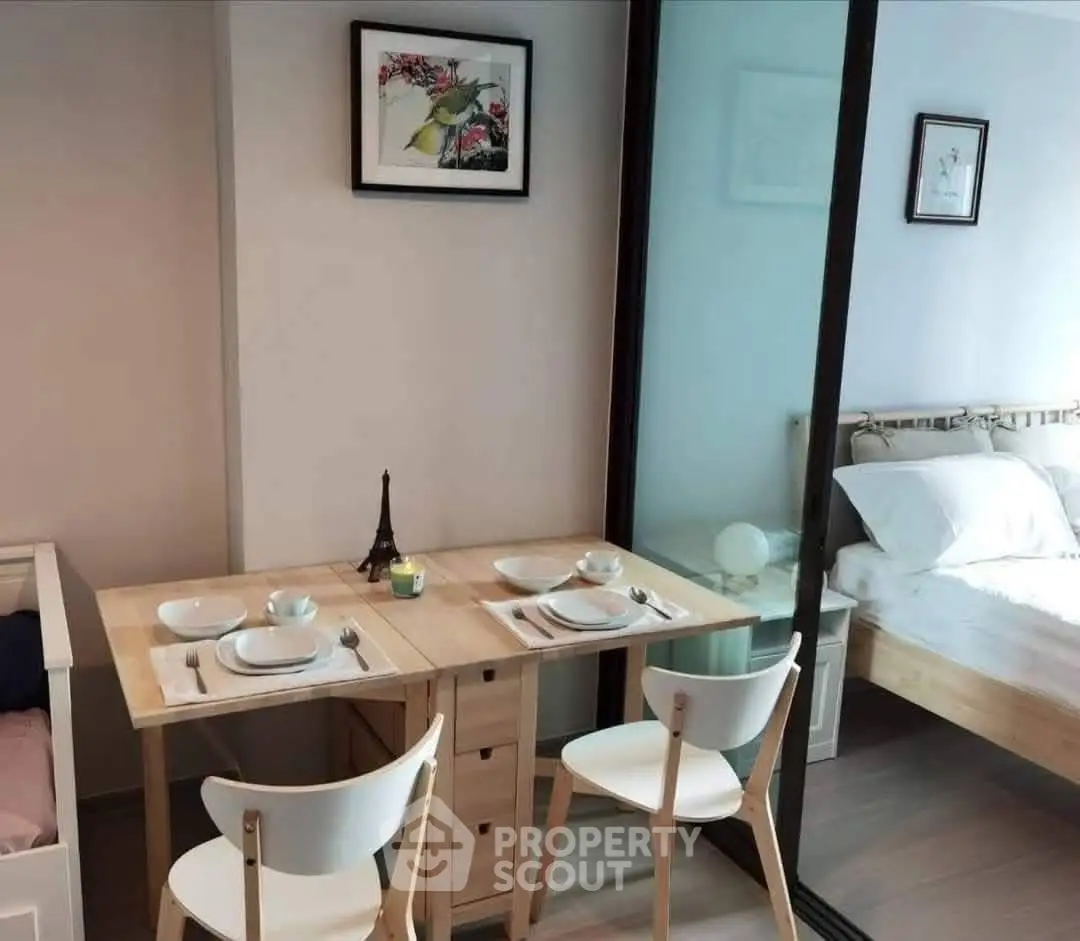 Cozy dining area with wooden table and chairs adjacent to a bright bedroom with sliding glass doors.