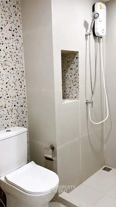 Modern bathroom with sleek shower and terrazzo tiles, perfect for contemporary living.