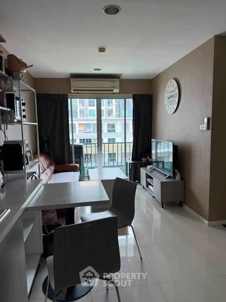 Modern living room with sleek furniture and large window offering natural light and city view.