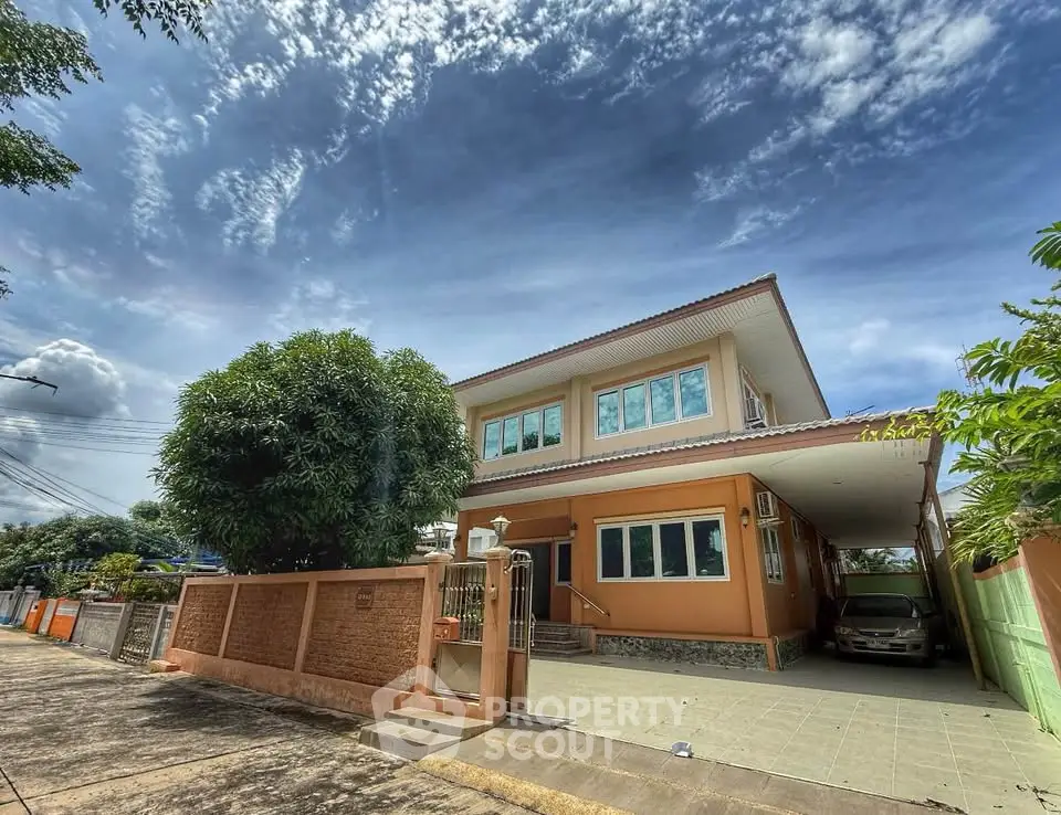 Charming two-story house with spacious driveway and lush greenery under a vibrant sky.