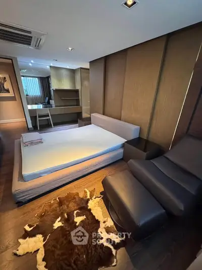 Modern bedroom with stylish furniture and cozy decor, featuring a unique cowhide rug and sleek design elements.